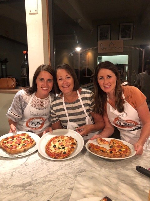Three women with plates of pizza they have made