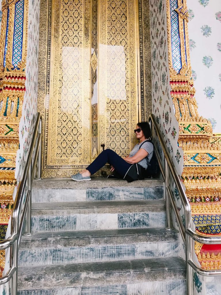 Woman sitting on steps of temple in Thailand