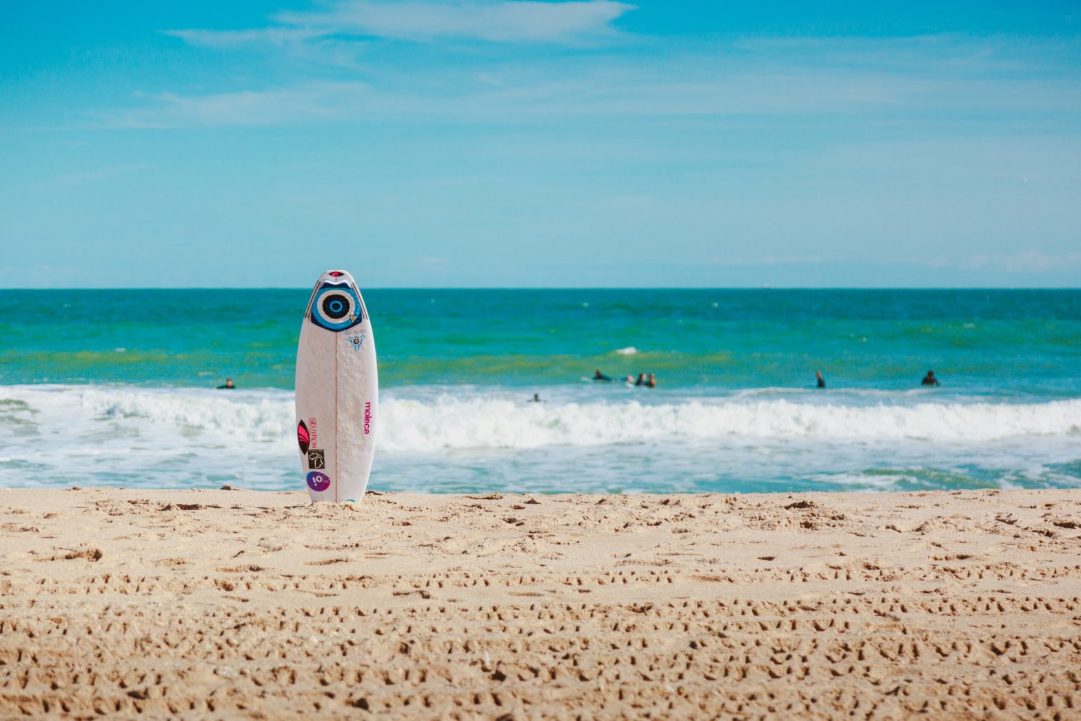 surfboard standing in sand near ocean