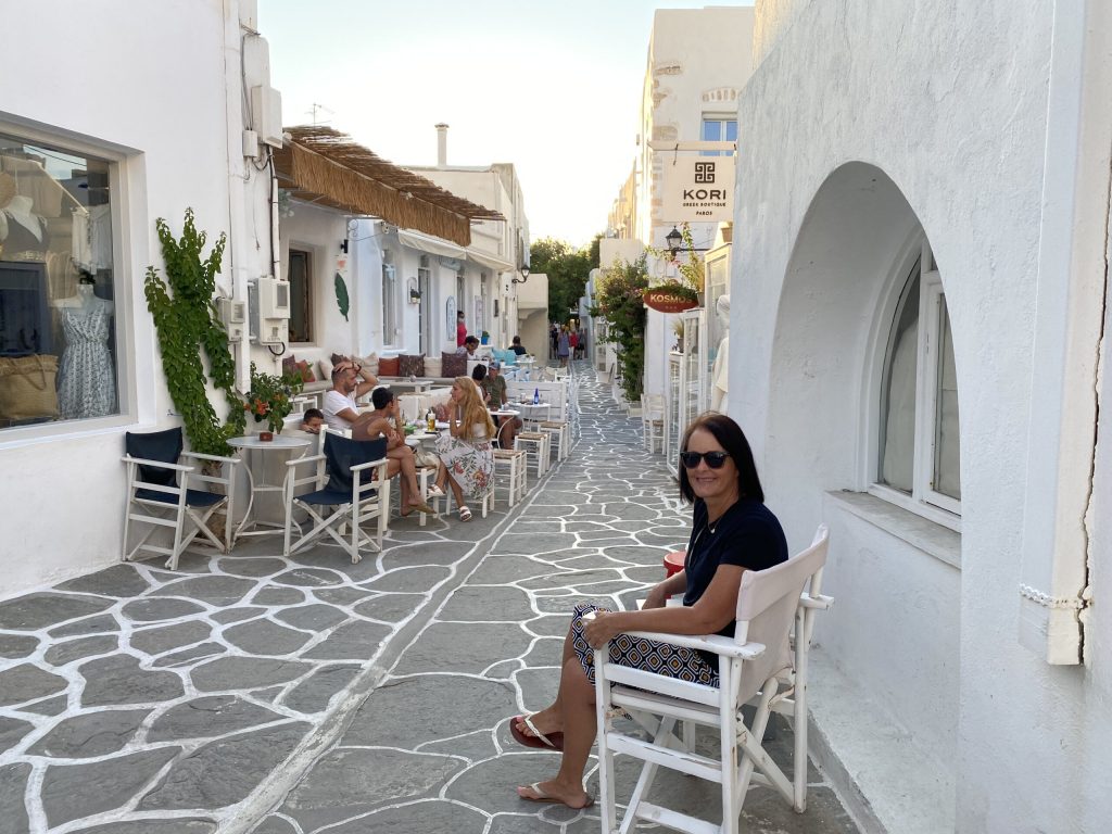 Woman sitting in white rocking chair on cobbled street