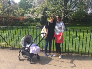 2 women and stroller in front of bushes