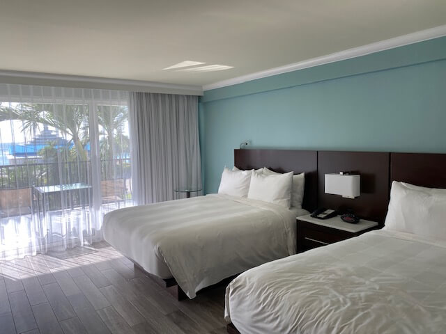 Two beds with white covers against blue wall