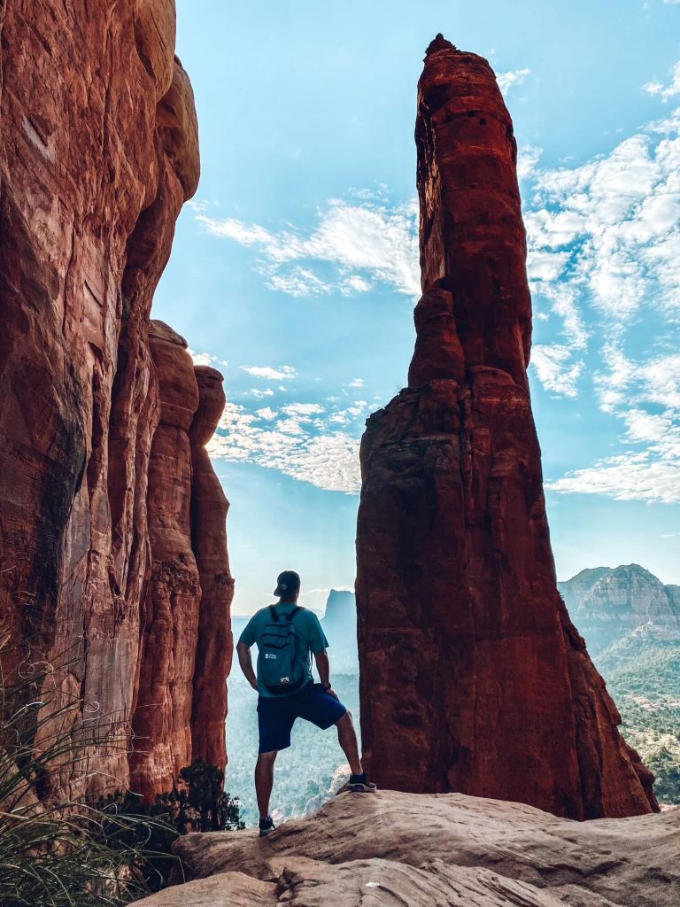 Man standing with his back towards us in between red rock spires
