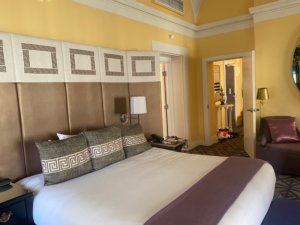 Hotel room with yellow walls and large bed with white cover