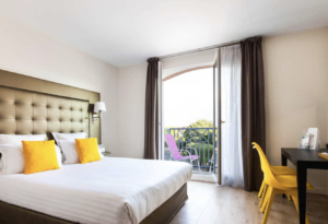 Hotel room with white bed and bright yellow pillows