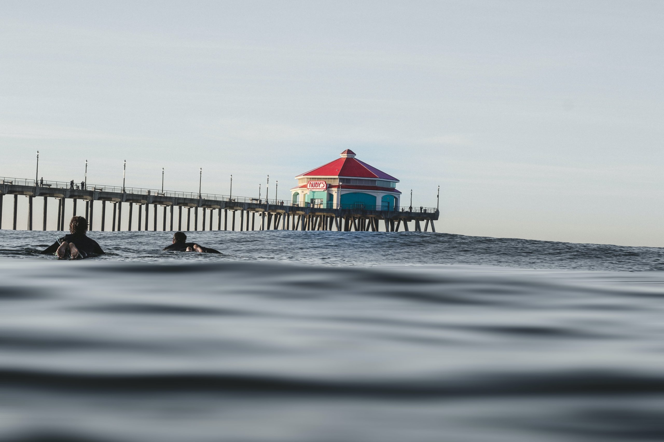 Ocean pier with surfer in foreground