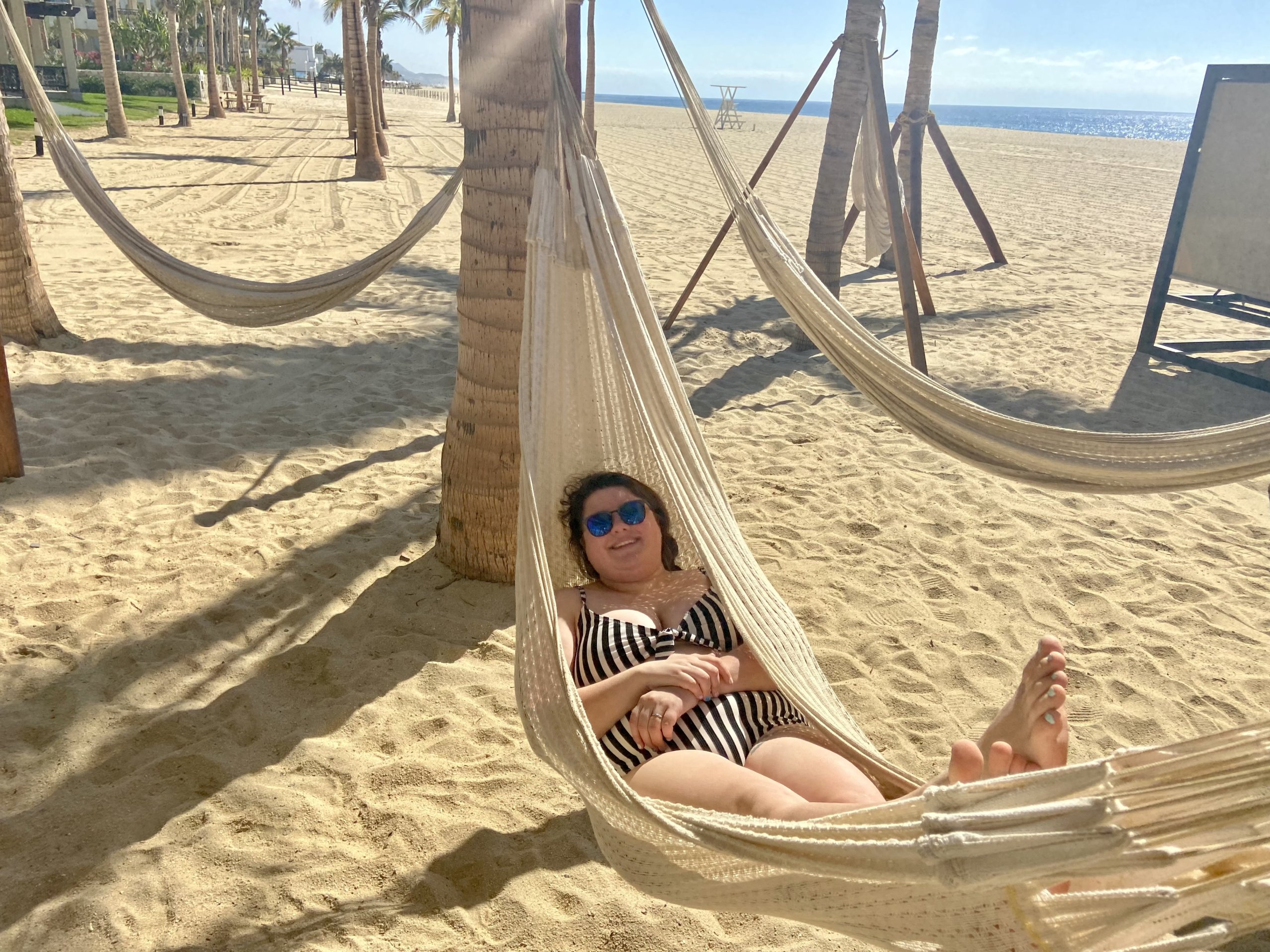 Woman laying in hammock above sand
