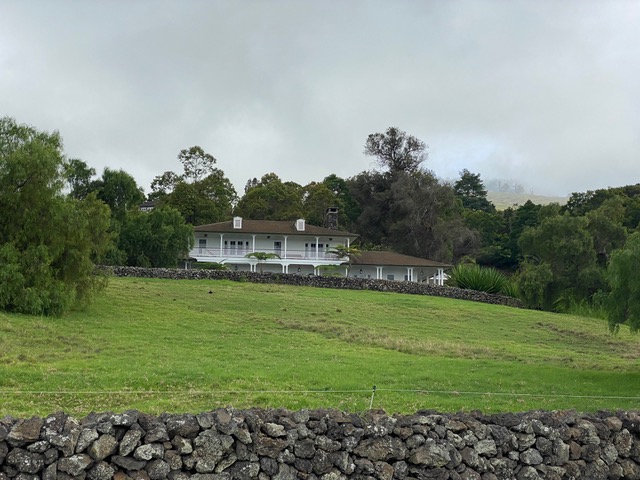 Large White House in green meadow.