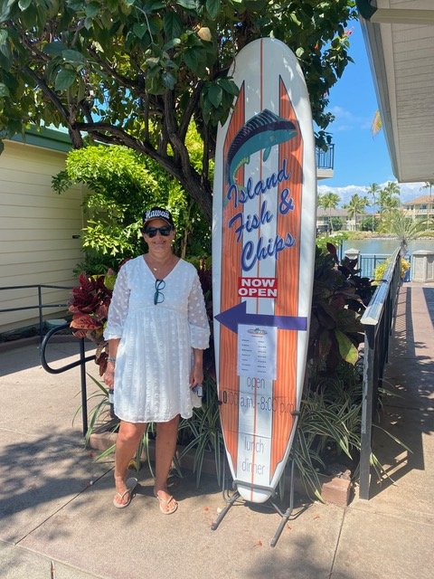 Woman standing by surfboard that says Island Fish and Chips