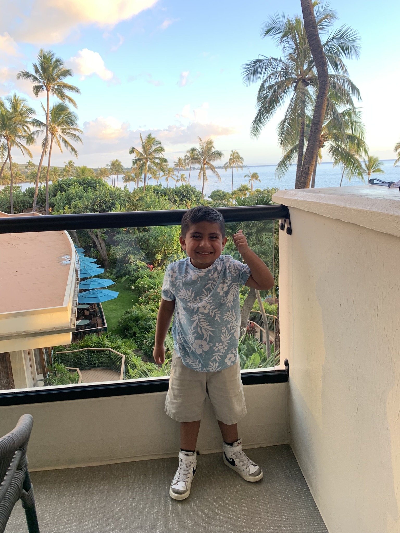 Small boy on hotel balcony with palm trees