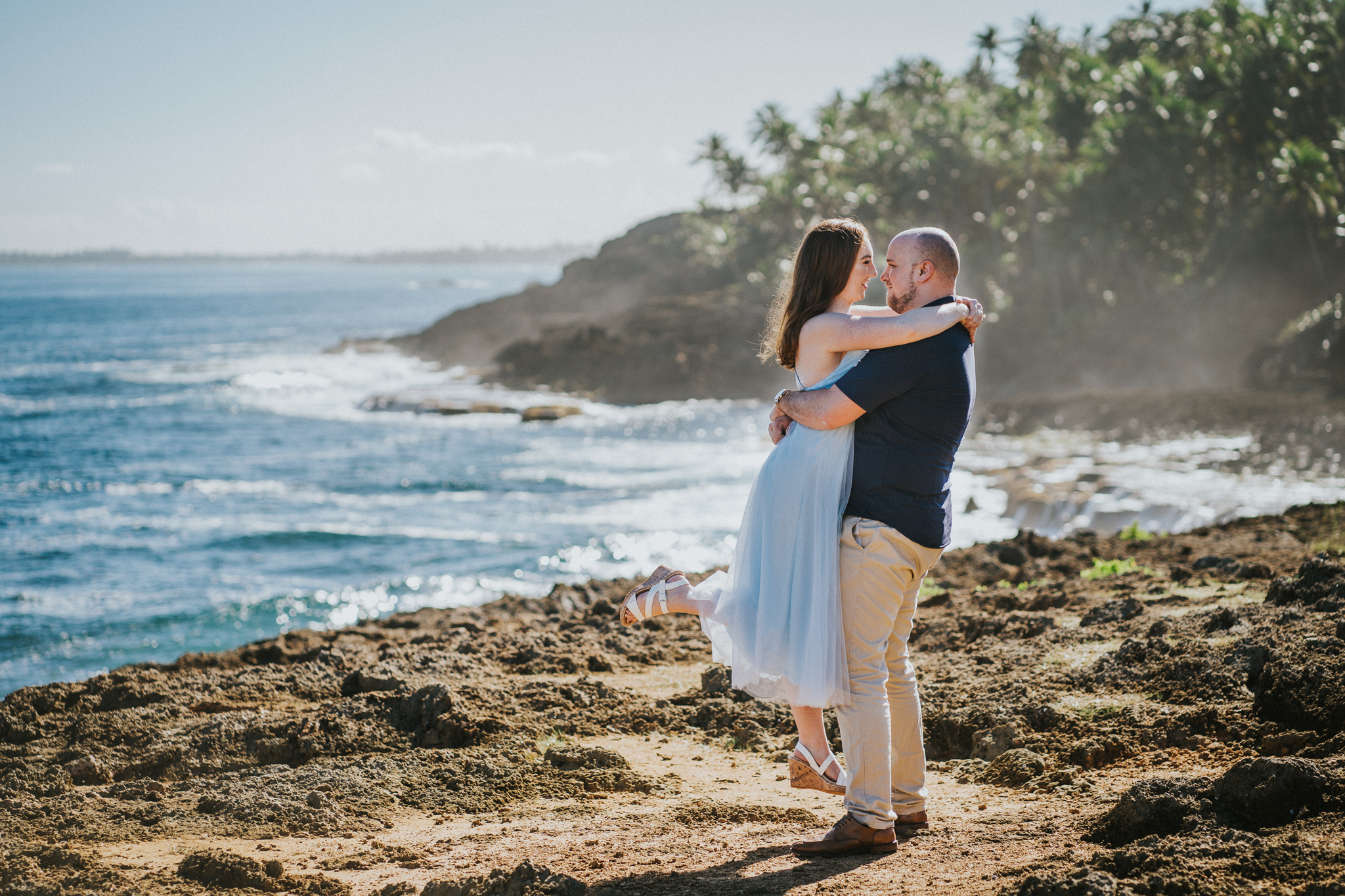 Man hugging girl in blue dress on beach