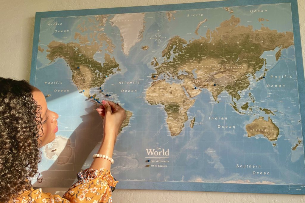 Person putting push pins in map of the world