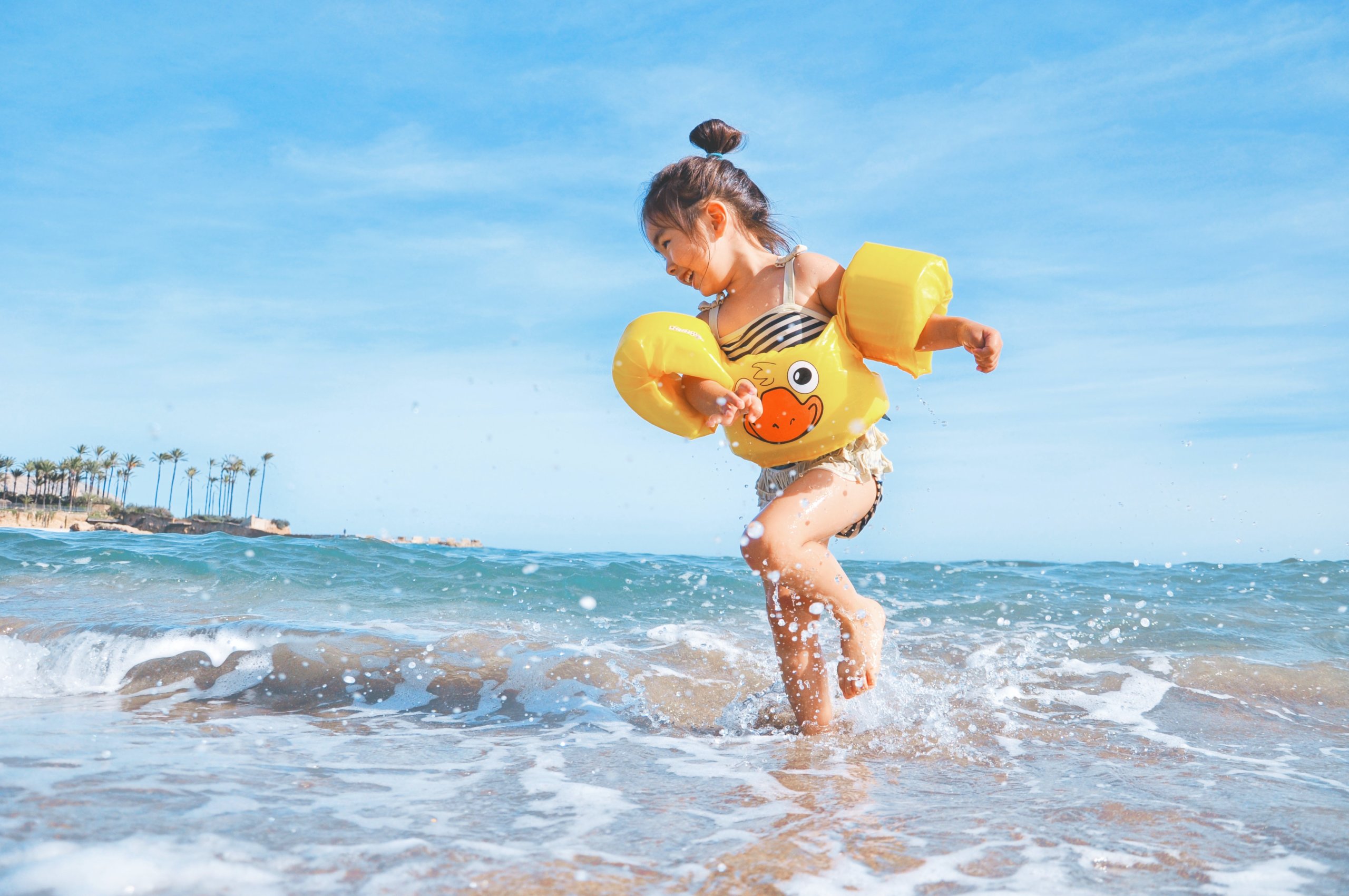 Young girl with duck water wings on playing in ocean