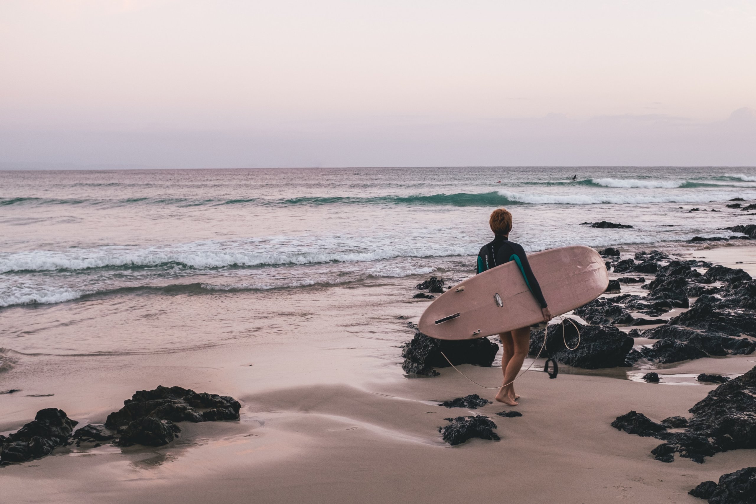 Woman on beach holding surfboard