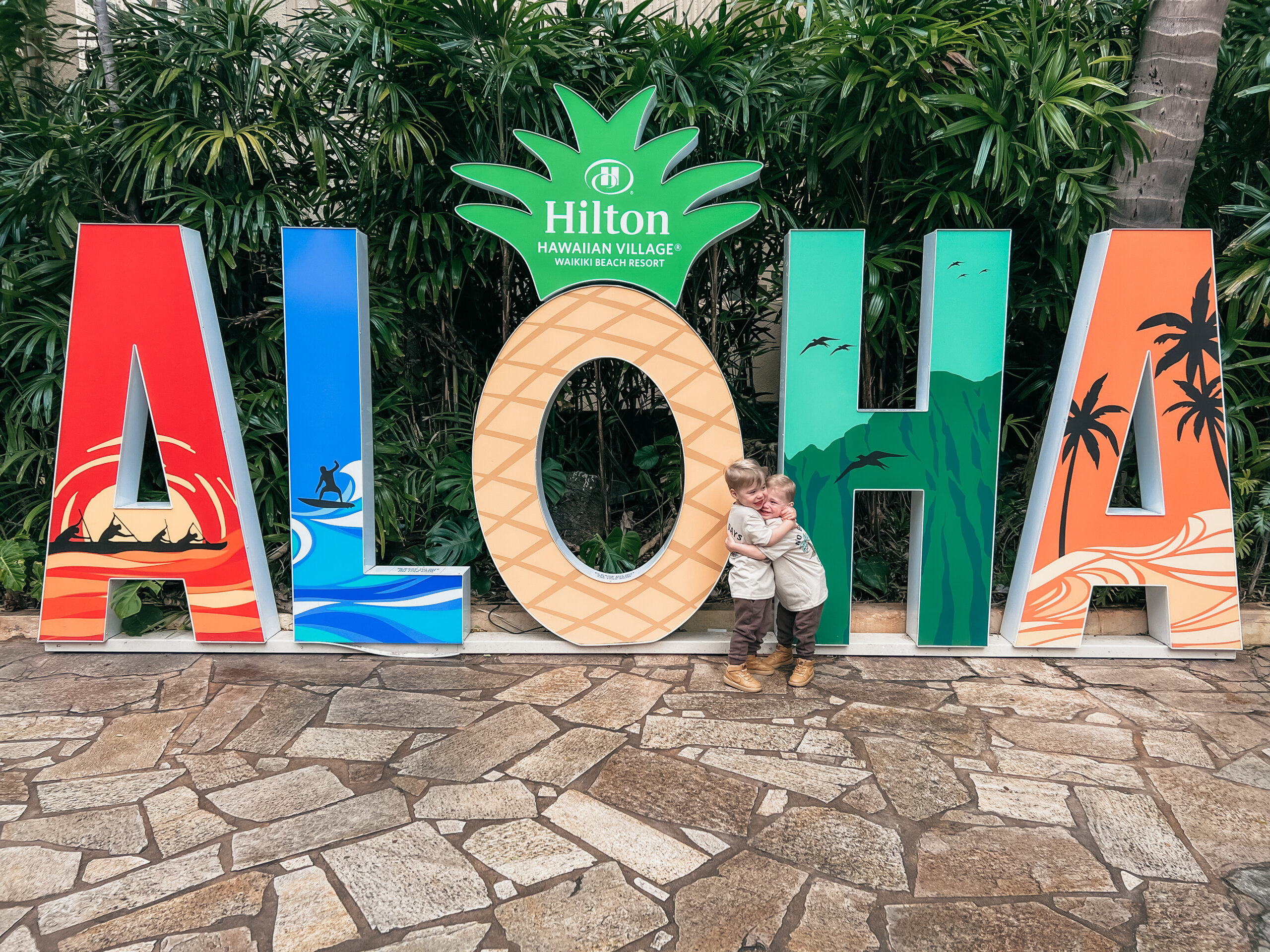 Two boys hugging by Aloha sign