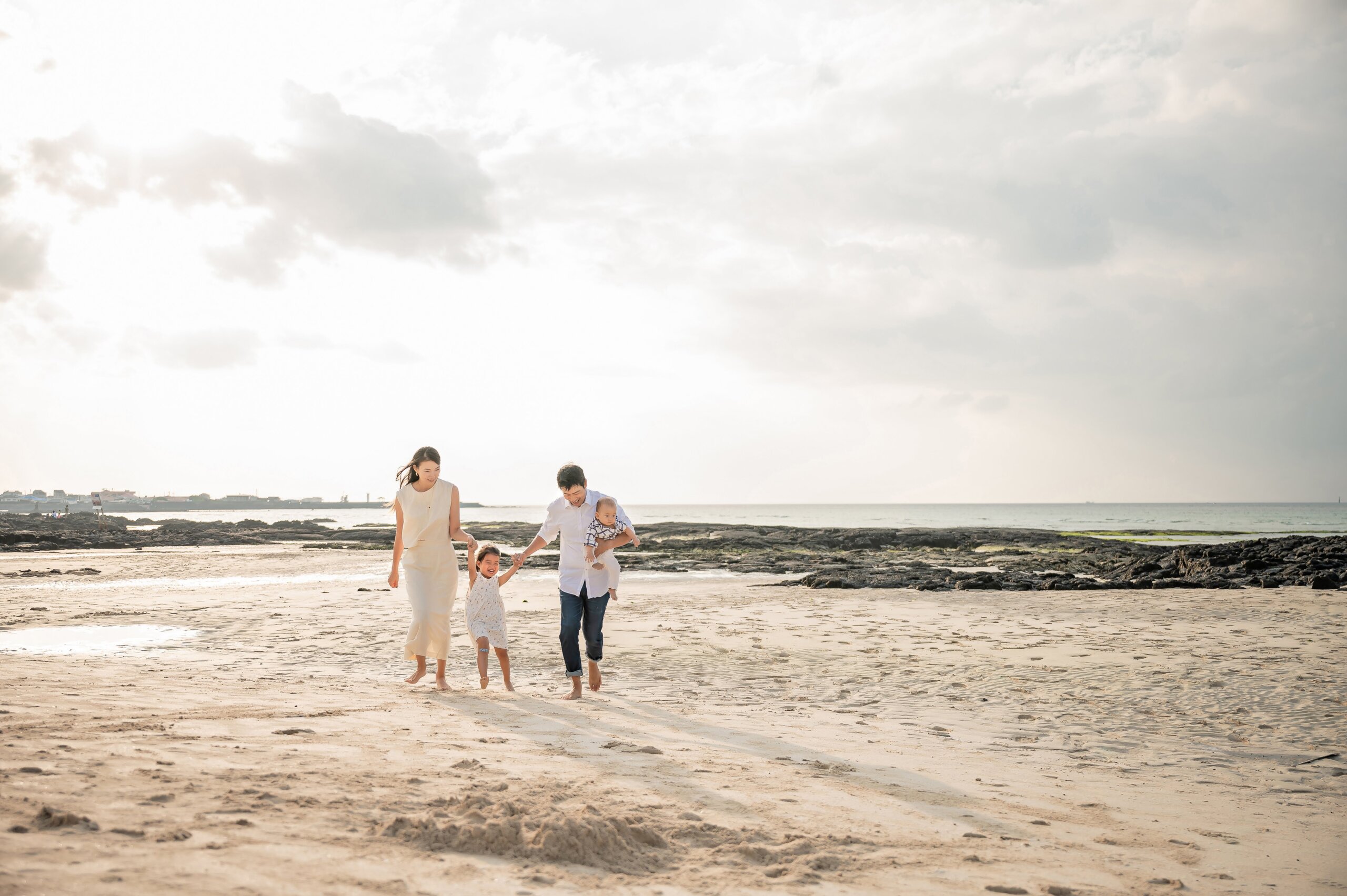 Man and woman walking on beach with young girl and baby