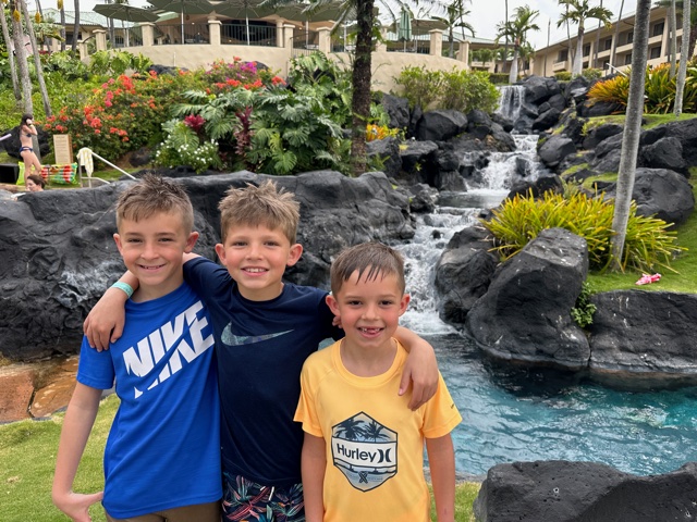 three boys near waterfall and pool area