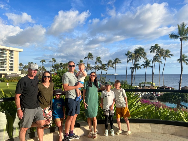 Family of 8 standing near palm trees and ocean