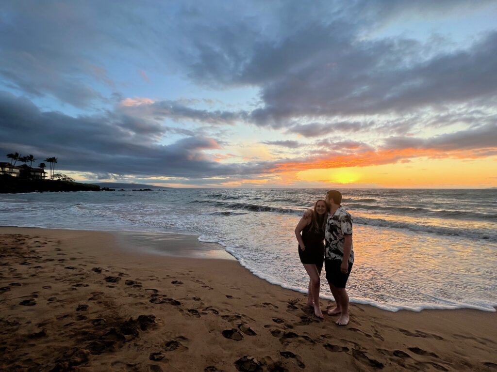 Man and woman on beach at sunset.